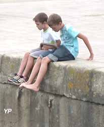 deux enfants assis sur le quai du port