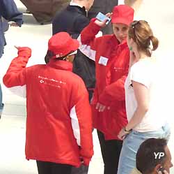 un gilet rouge renseigne une voyageuse gare de Lyon